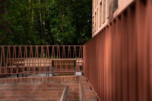 Red brick, bronze aluminium, and cast stone details at Queens Business School demonstrating award winning UK architecture, material restraint, and sensitive design by Todd Architects, captured by Donal McCann Photography.