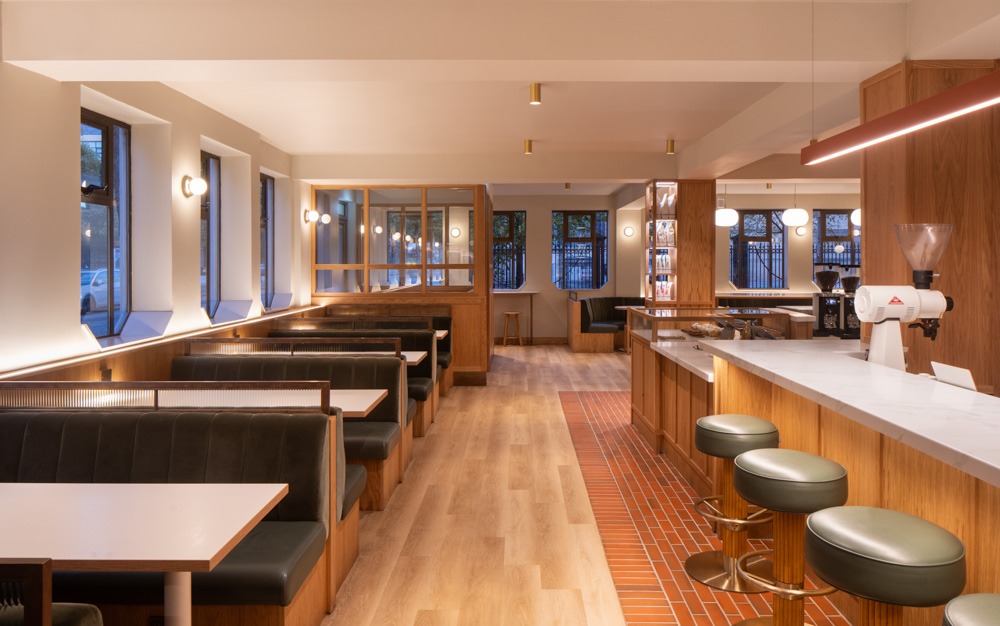 Interior of Neighbourhood Café in Belfast featuring central bar, oak panelling, and cozy seating in a warm, inviting space.
