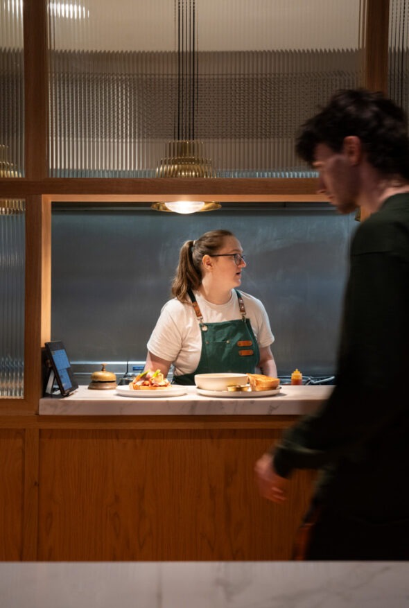 Open kitchen at Neighbourhood Café in Belfast, chefs preparing fresh brunch dishes, showcasing Ireland’s best cafe experience.