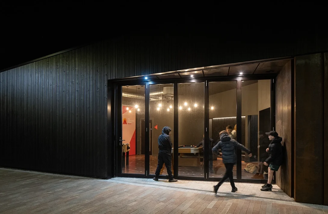 Night shot of children playing outside the Lighthouse Project youth hub in Byker, showing vibrant community use.