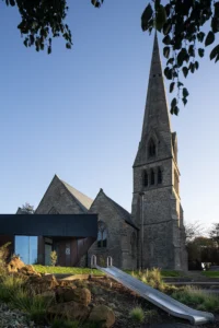 Exterior view of the Lighthouse Project showing the contemporary extension blending with historic St Michael’s Church in Byker.