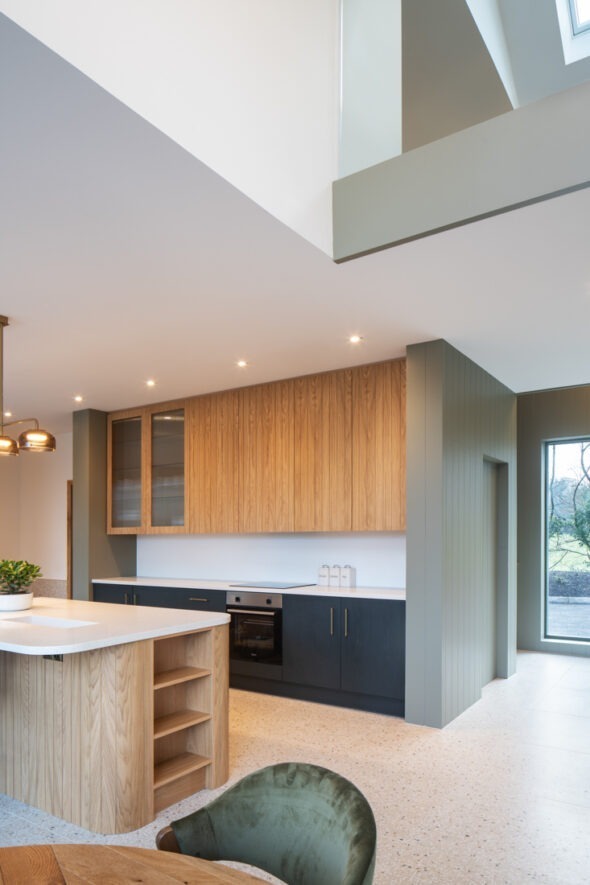 Open-plan kitchen and lounge illuminated by soft early light — modern interiors at The Chalet by Nest Architects.